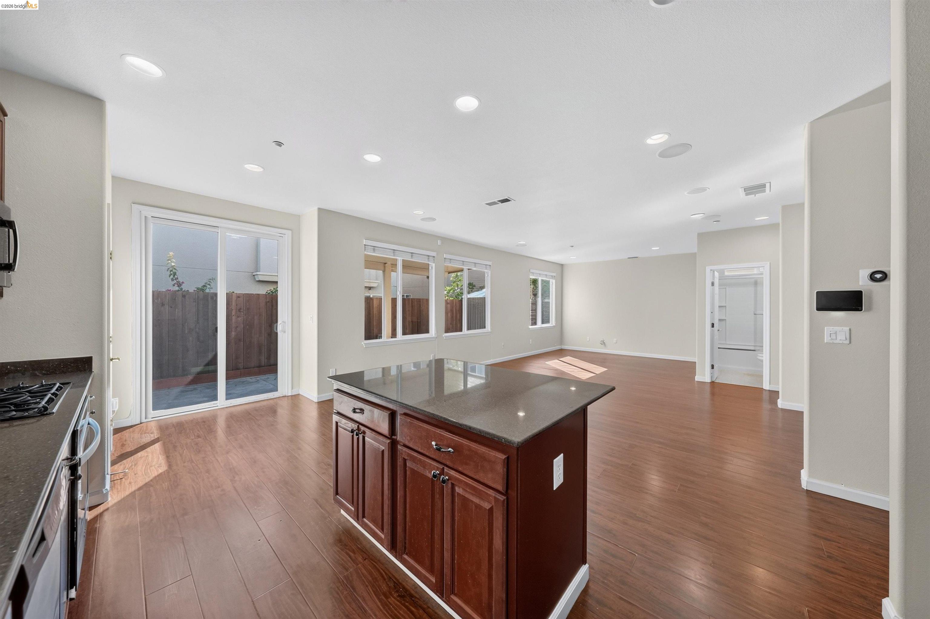 Open kitchen and living area with a dark wood island, hardwood floors, and sliding glass doors.