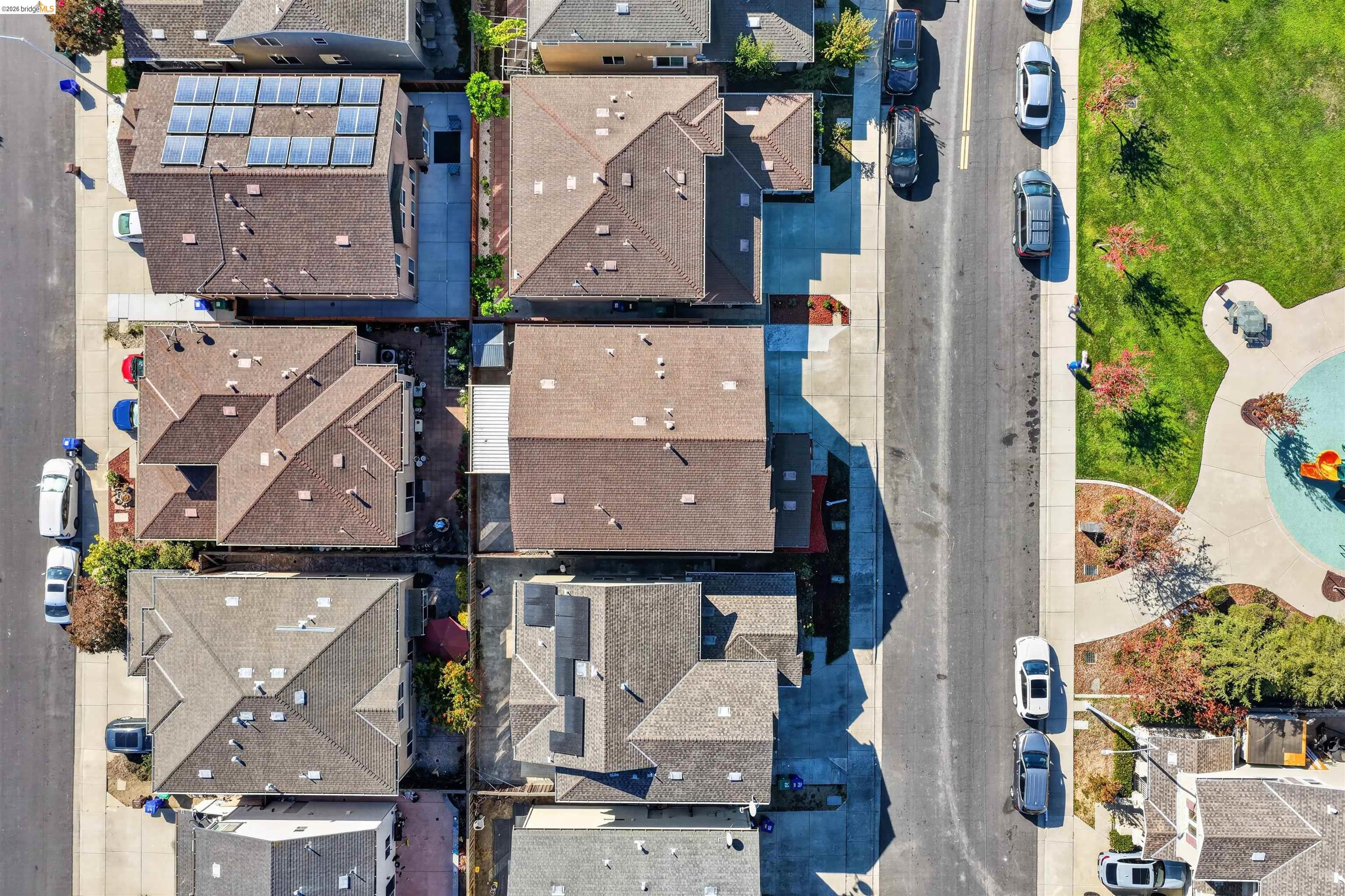 Aerial view of closely spaced homes beside a landscaped community pool and park.
