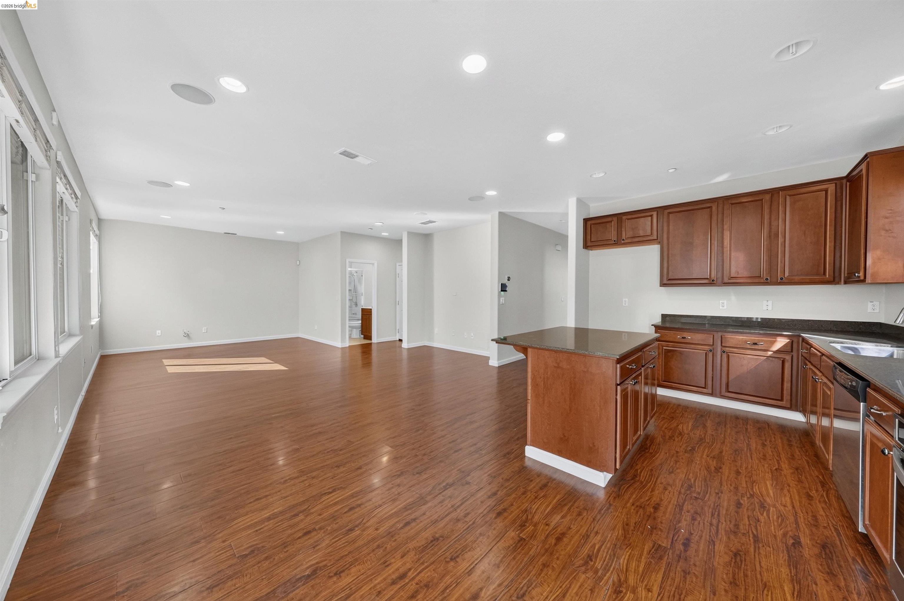 Open kitchen and living area with wood cabinets, a central island, and hardwood floors.