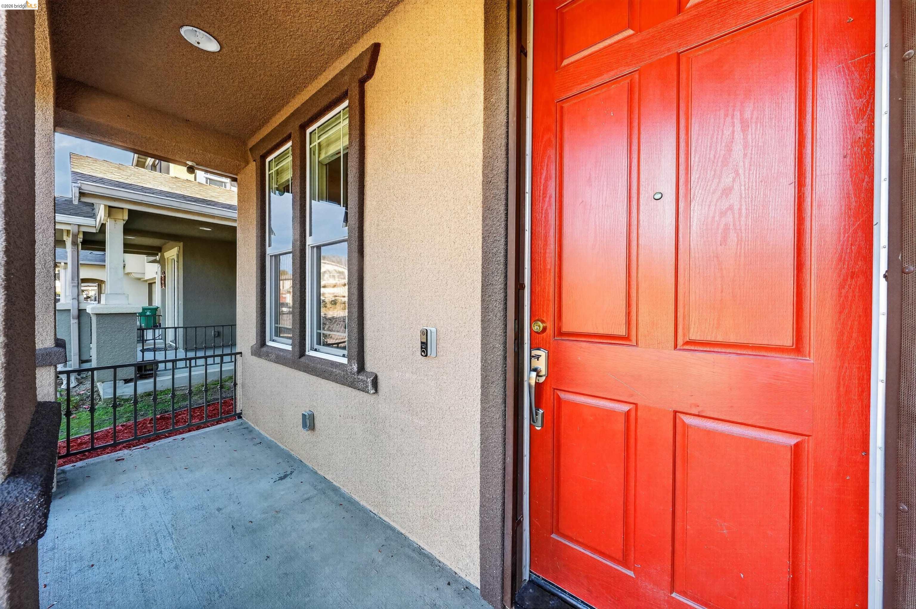 Covered front porch with a vivid red paneled entry door and adjacent windows.