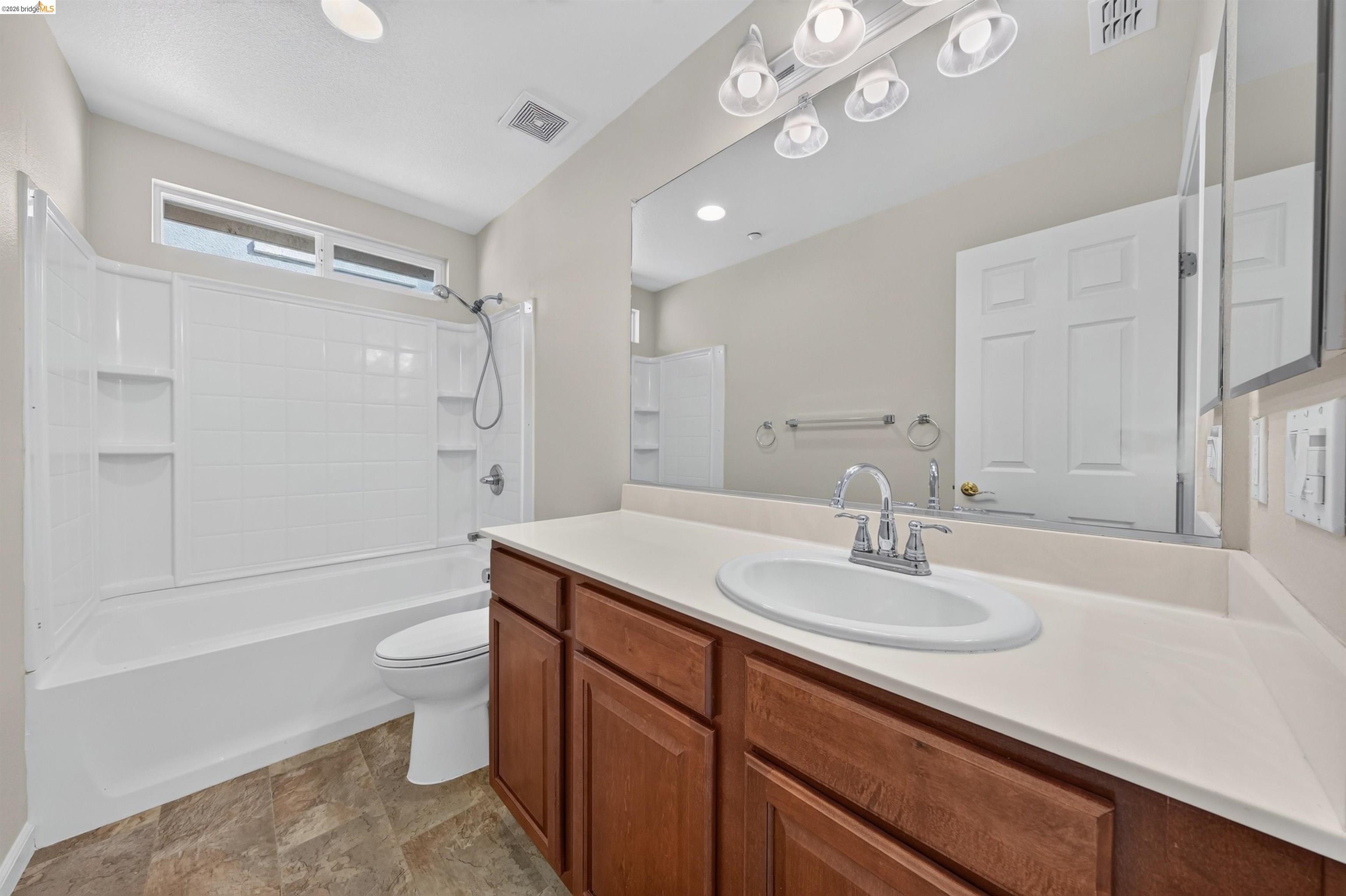 Bathroom with a tub and shower, wide vanity with a wood cabinet, and large mirror.