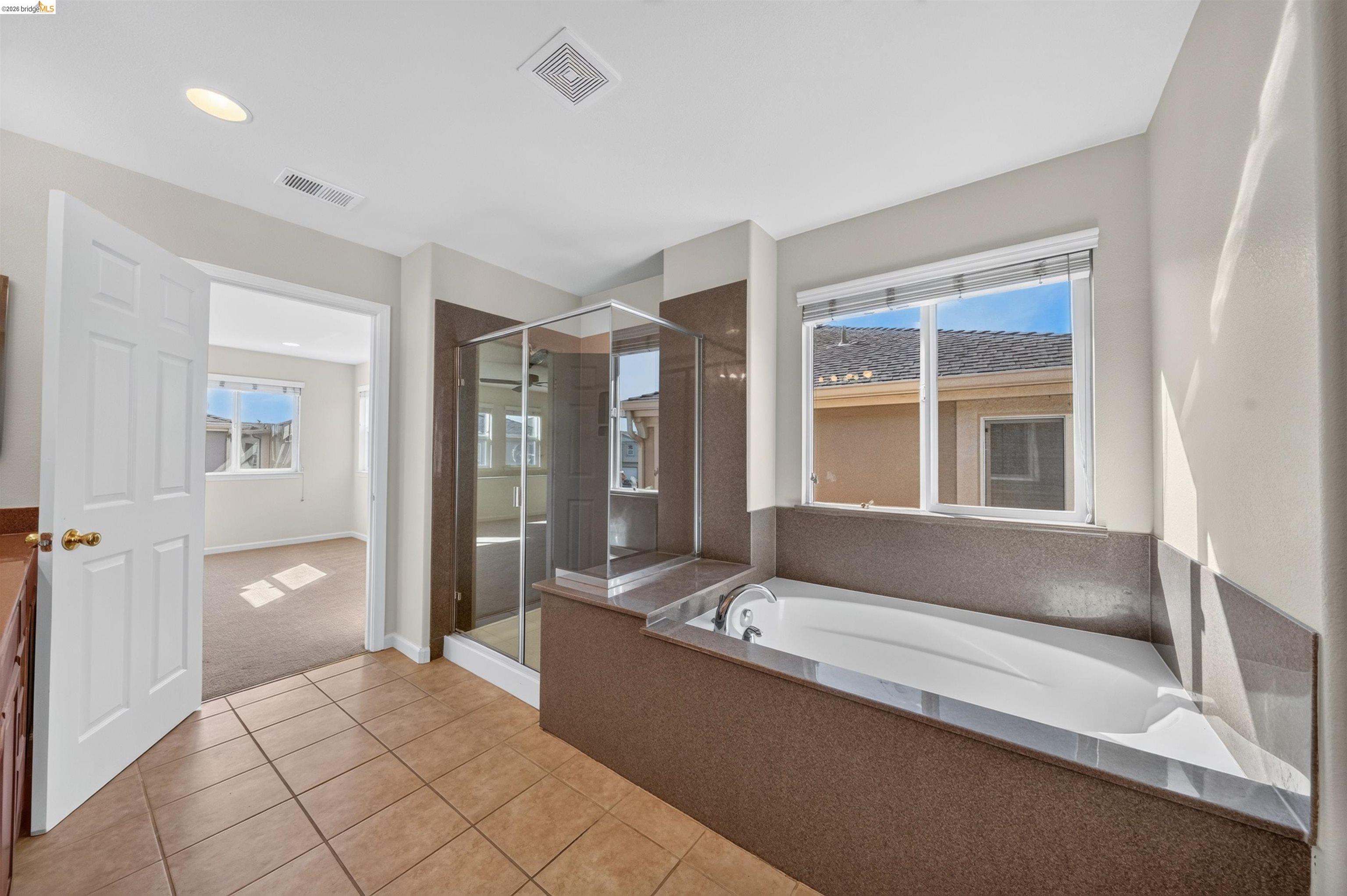 Bathroom with a glass-enclosed shower and a built-in soaking tub beside a large window.