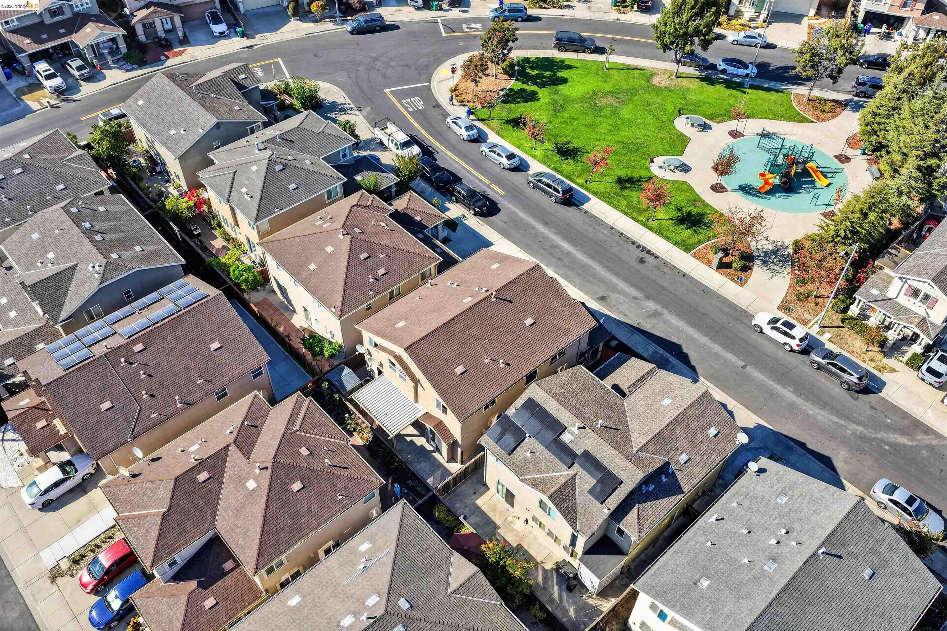 Aerial view of homes beside a neighborhood park with a playground and walking paths.