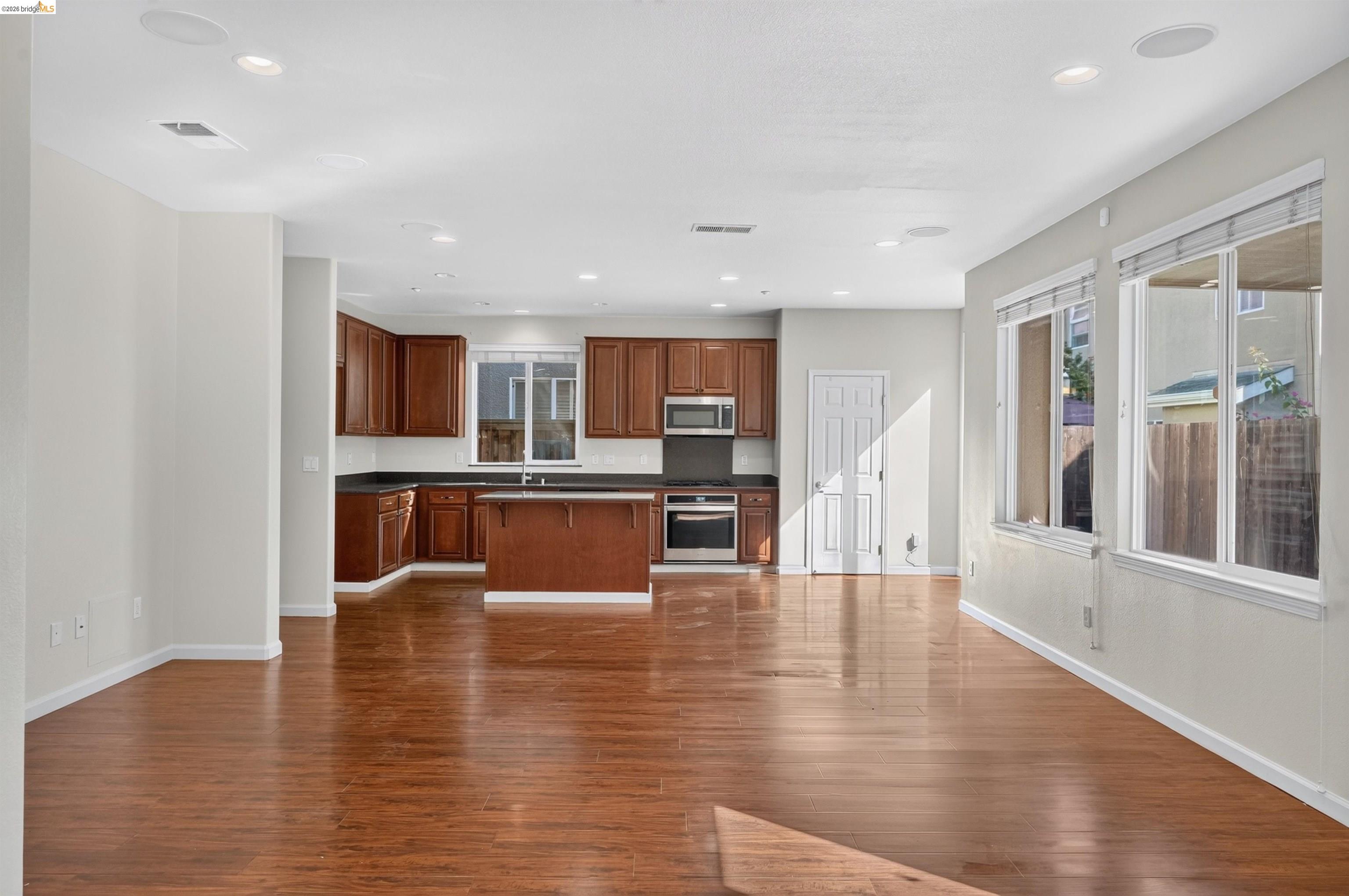 Open kitchen and dining area with dark wood cabinets, a central island, and large windows.