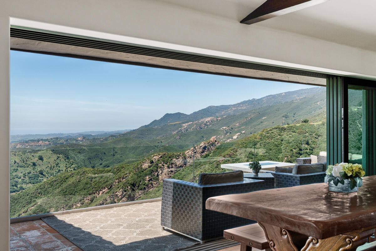 Dining area opens to a furnished terrace overlooking green mountain ridges.