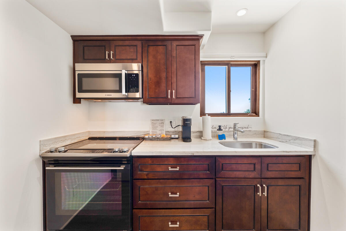 Kitchen with dark wood cabinets, marble-look counters, and a window above the sink.