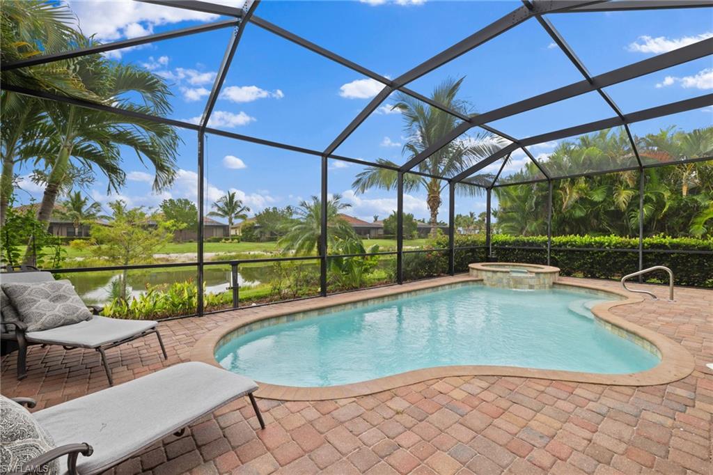Screened-in pool and raised spa with brick pavers, lounge chairs, and a waterway view.