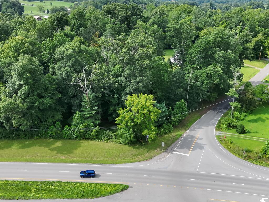 Aerial view of wooded land beside a grassy clearing at a highway intersection.