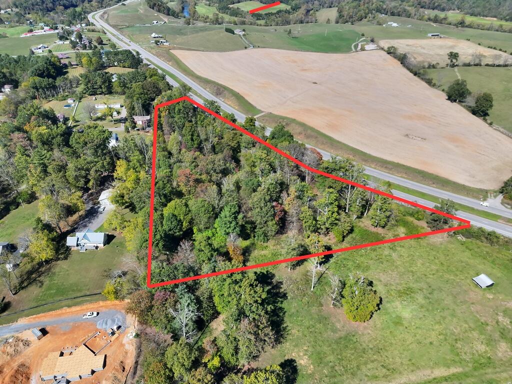 Aerial view of a wooded parcel outlined in red beside a rural highway.