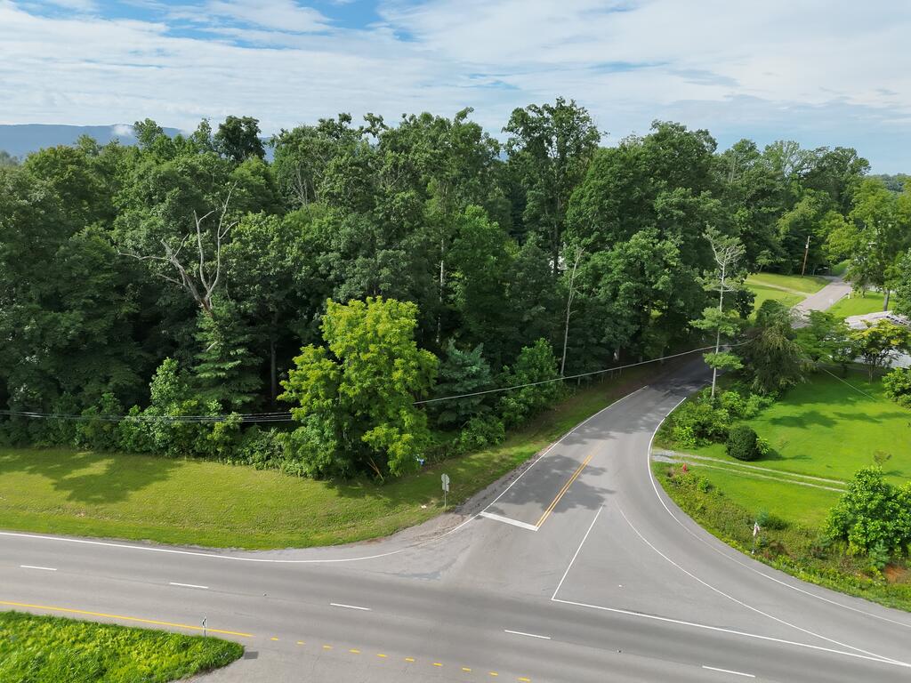 Aerial view of a wooded property beside a road intersection.