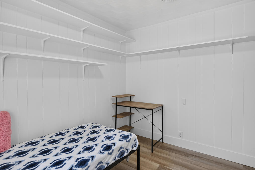 Bedroom with built-in wall shelves, a patterned bedspread, and a small desk.