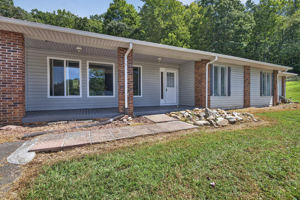 Single-story home with a covered porch, brick columns, and stone landscaping.