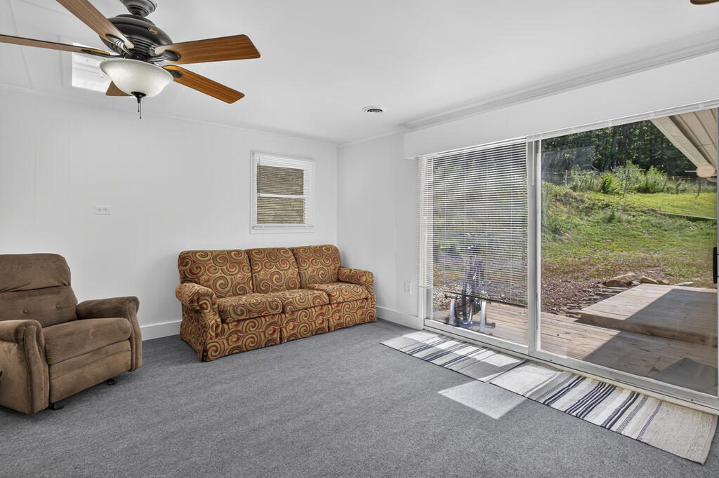Living room with patterned sofa, gray carpet, and sliding glass doors to a deck and yard.