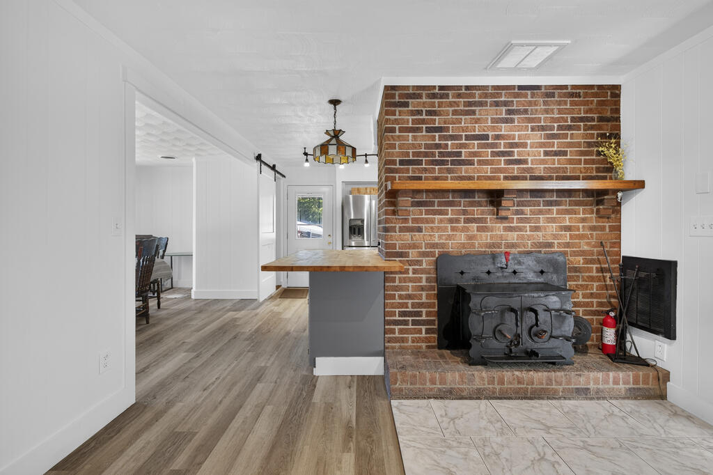 Living area with a brick fireplace and wood-burning stove beside an adjoining kitchen counter.