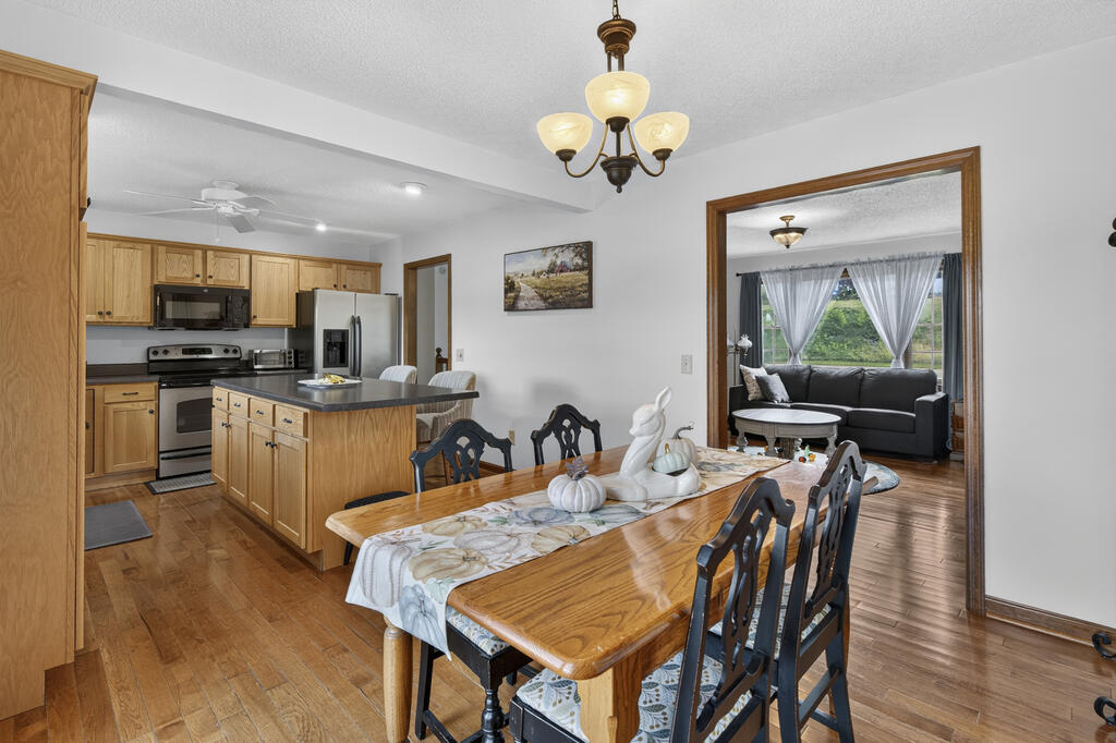 Dining room with a wooden table, adjoining a wood-cabinet kitchen and sitting room.