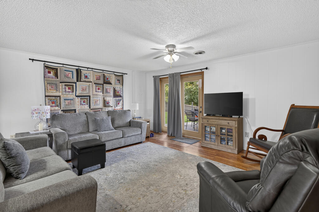 Living room with gray sofas, leather recliners, a patchwork quilt, and glass patio doors.