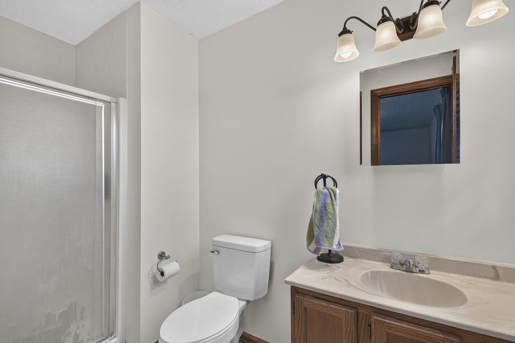 Bathroom with a glass shower enclosure, toilet, and wood vanity.