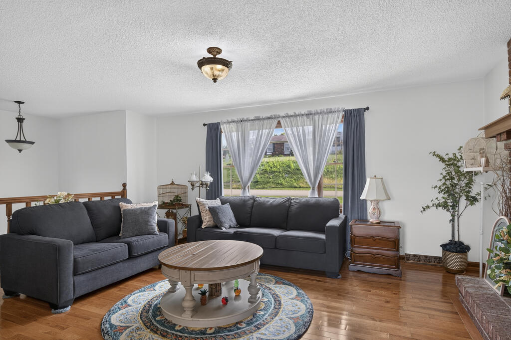 Living room with charcoal sofas, a round coffee table, and a large curtained window.