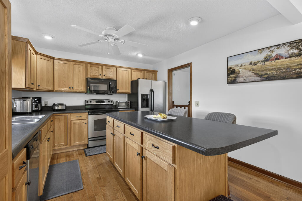 Kitchen with oak cabinets, stainless steel appliances, and a large dark-countertop peninsula.