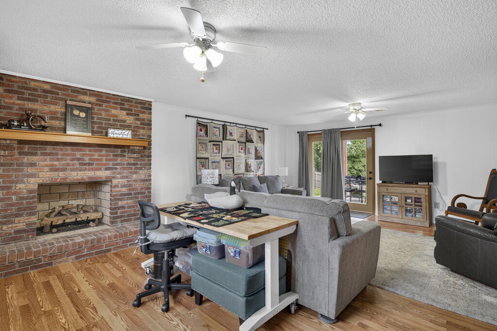 Living room with a brick fireplace, gray sectional, hardwood floors, and glass patio door.