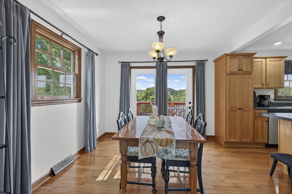 Dining room with a wooden table, adjoining wood-cabinet kitchen, and glass doors opening to a deck.