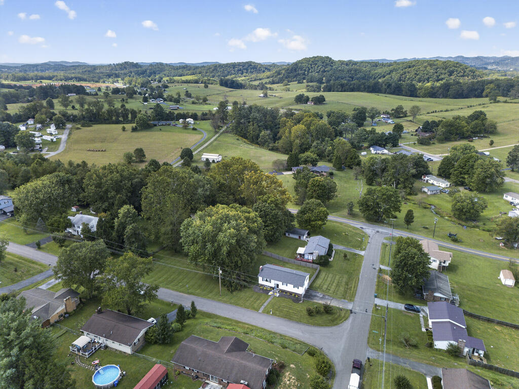 Aerial view of a rural neighborhood with scattered homes, fields, and wooded hills.