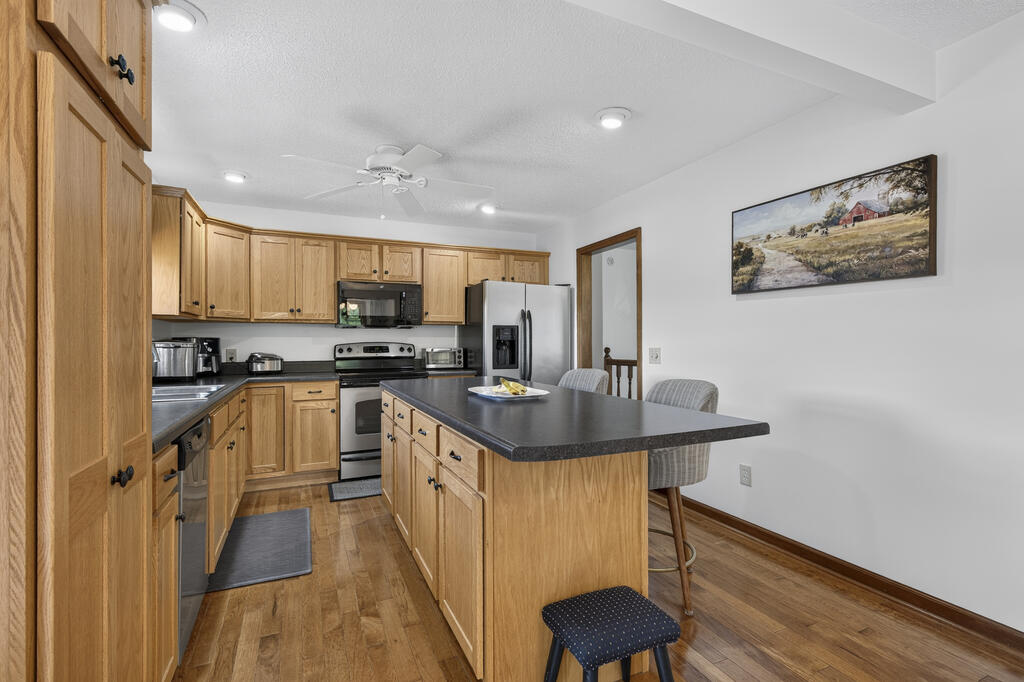 Kitchen with wood cabinetry, a dark island countertop, and stainless steel appliances.