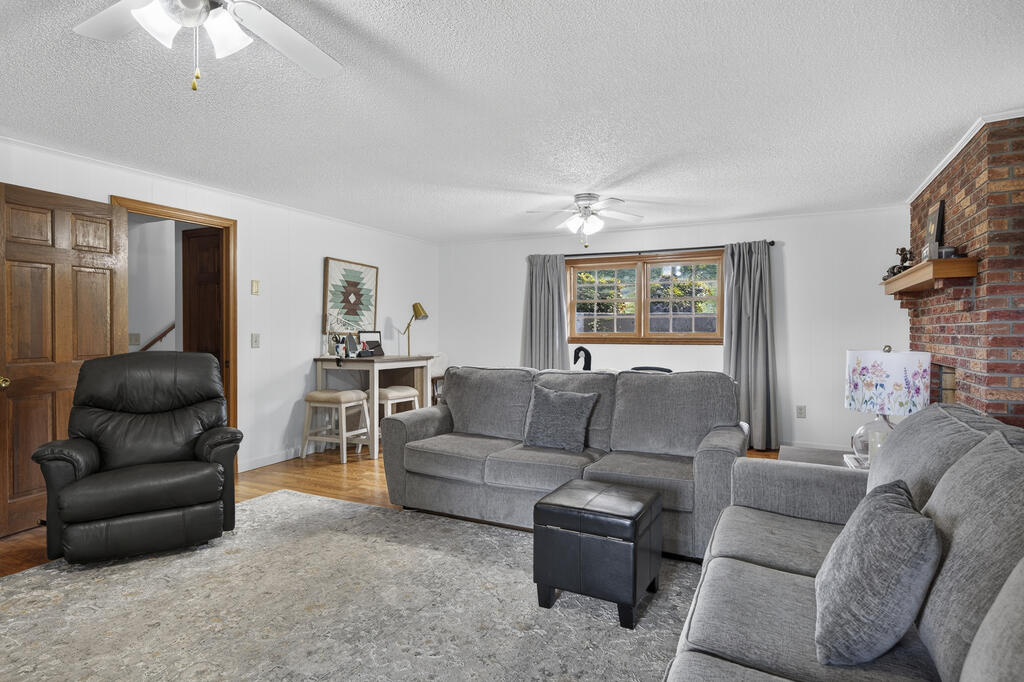 Living room with gray sofas, a black recliner, and a brick fireplace.