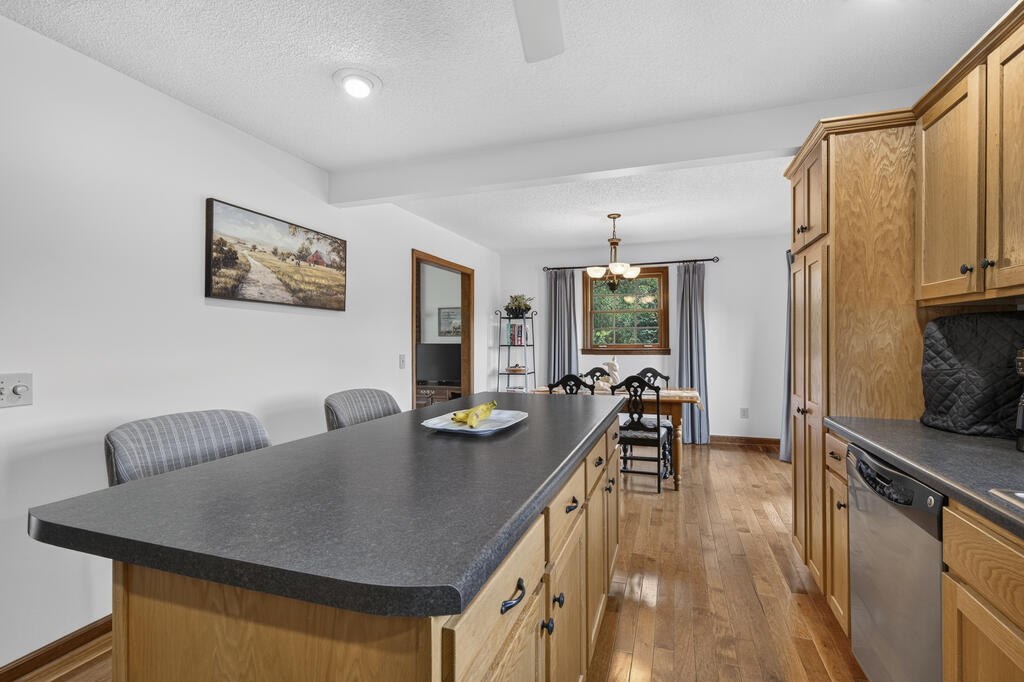 Kitchen with a long dark island and wood cabinetry opening to a dining area.