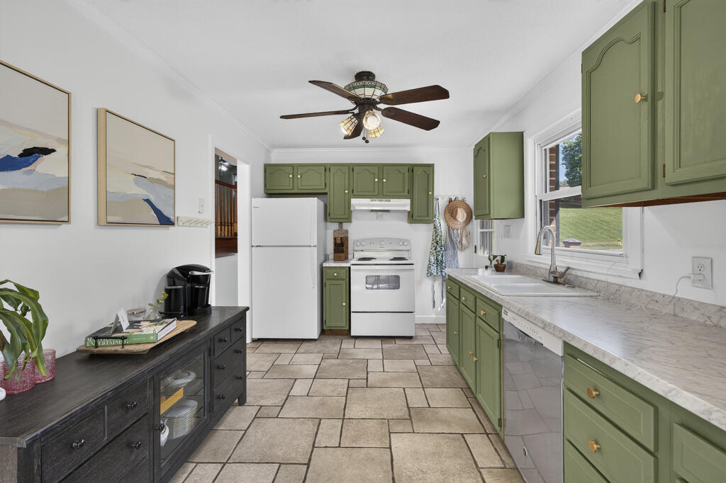 Kitchen with sage-green cabinets, white appliances, and a large tiled floor.