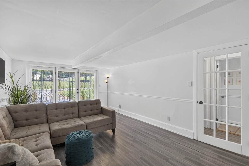 Living room with a gray sectional, teal ottoman, and tall gridded windows.