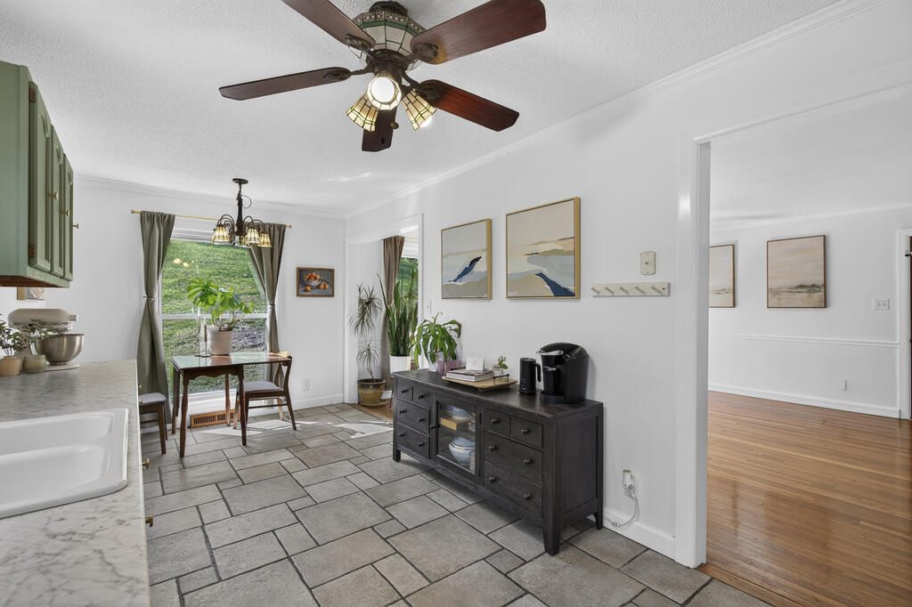 Kitchen and dining area with gray tile floors, green cabinets, and a small table by the window.