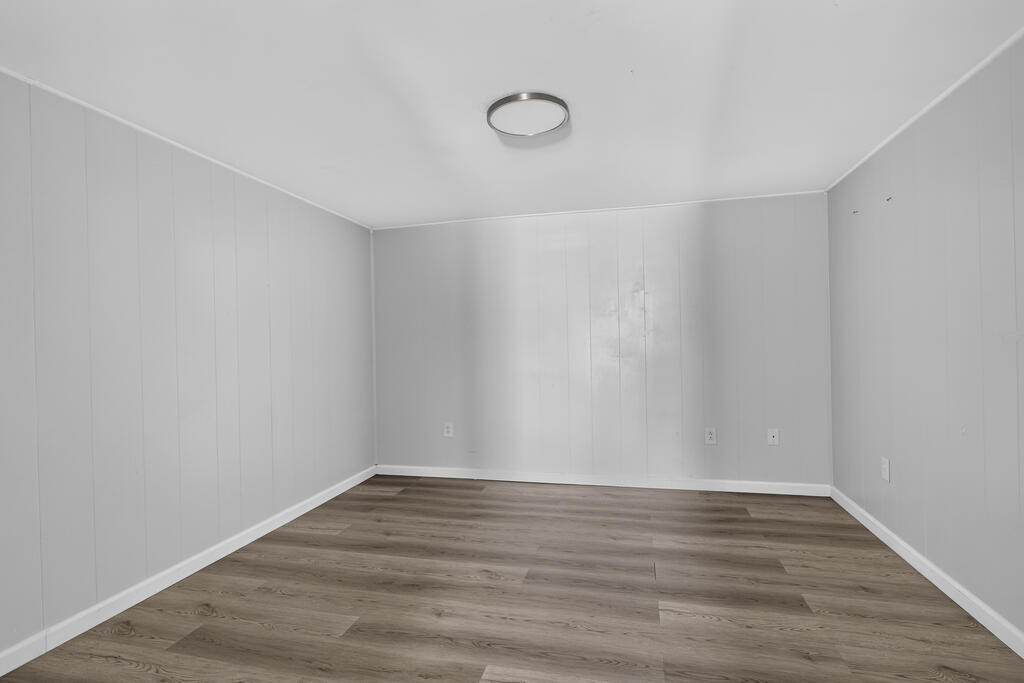 Empty room with gray paneled walls and gray-brown plank flooring.