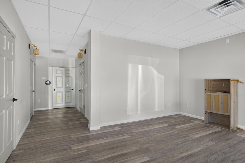 Vacant room with gray plank flooring, white paneled doors, and a small wooden cabinet.