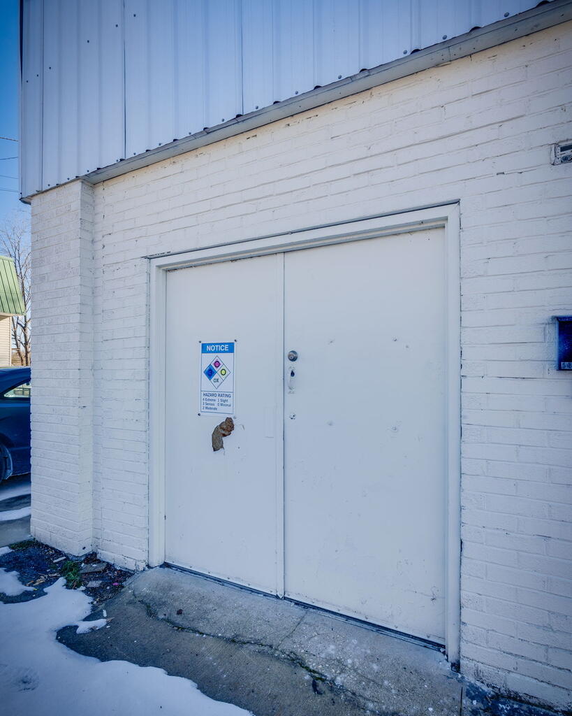 White brick building exterior with metal utility doors and patches of snow.