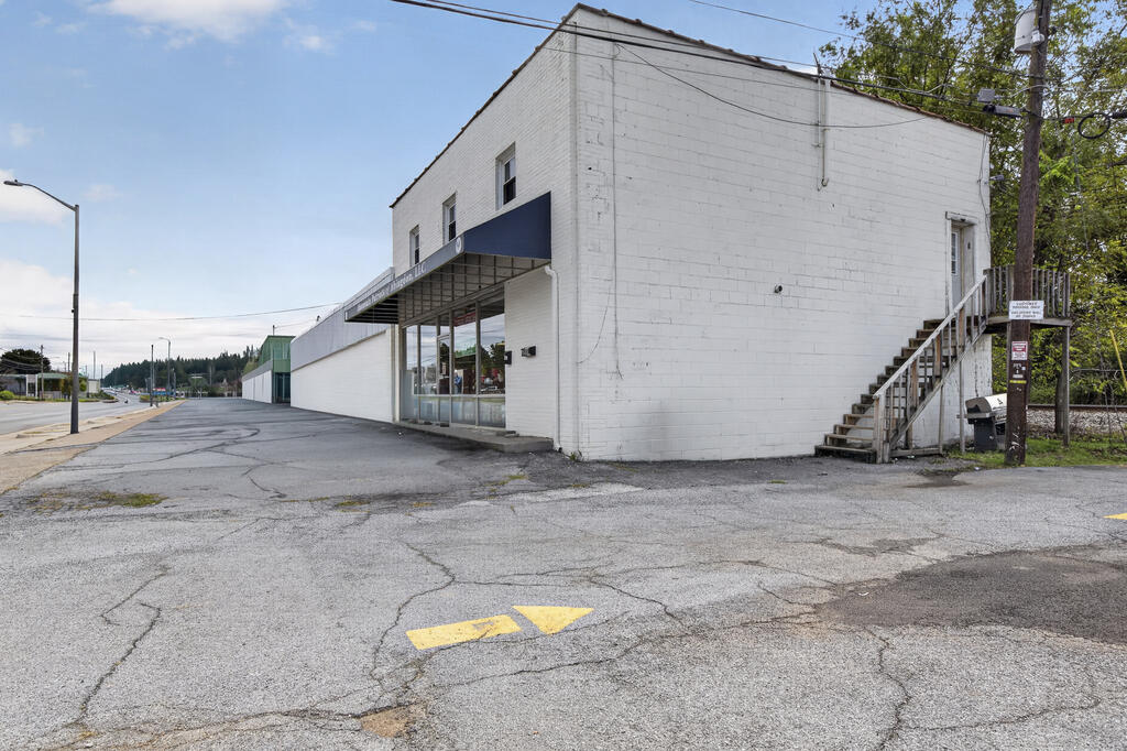 White two-story commercial building with a blue storefront awning and exterior stairs.