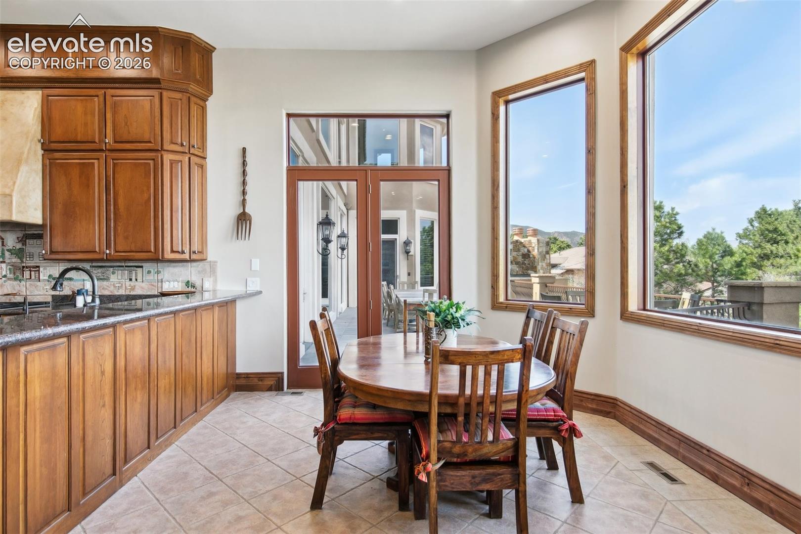 Kitchen dining area with wood cabinetry, a round table, and large windows overlooking hills.