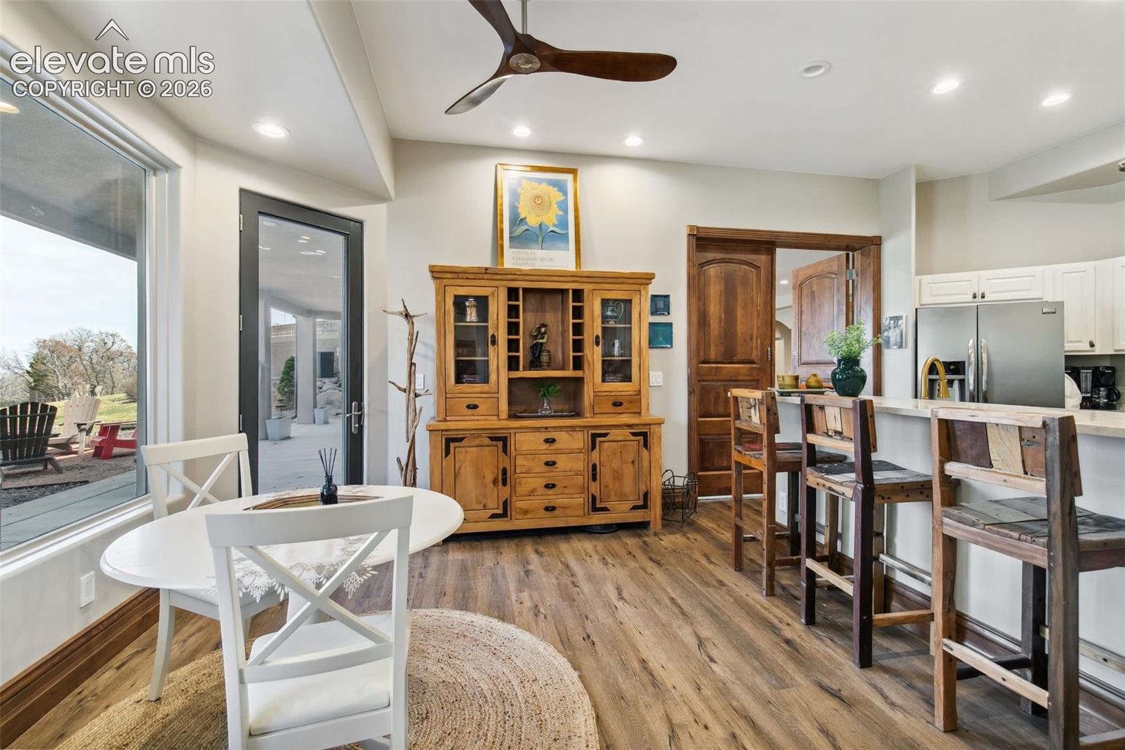 Dining area with a white round table, rustic wooden hutch, and kitchen bar seating.