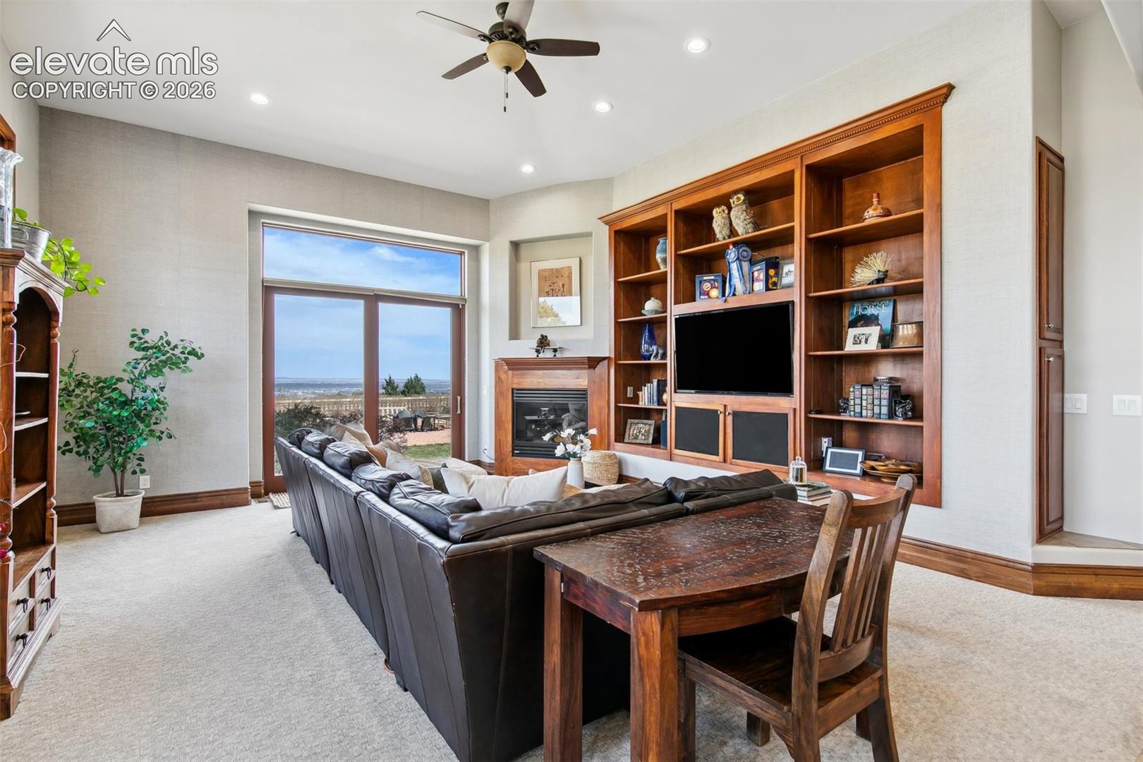 Living room with built-in wooden entertainment center, fireplace, and window overlooking the landscape.