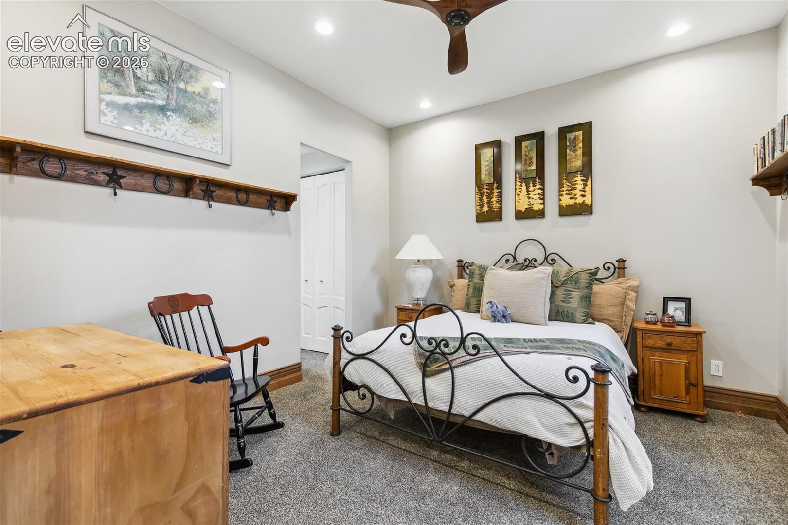 Bedroom with an ornate black metal bed, rustic wood accents, and forest-themed artwork.