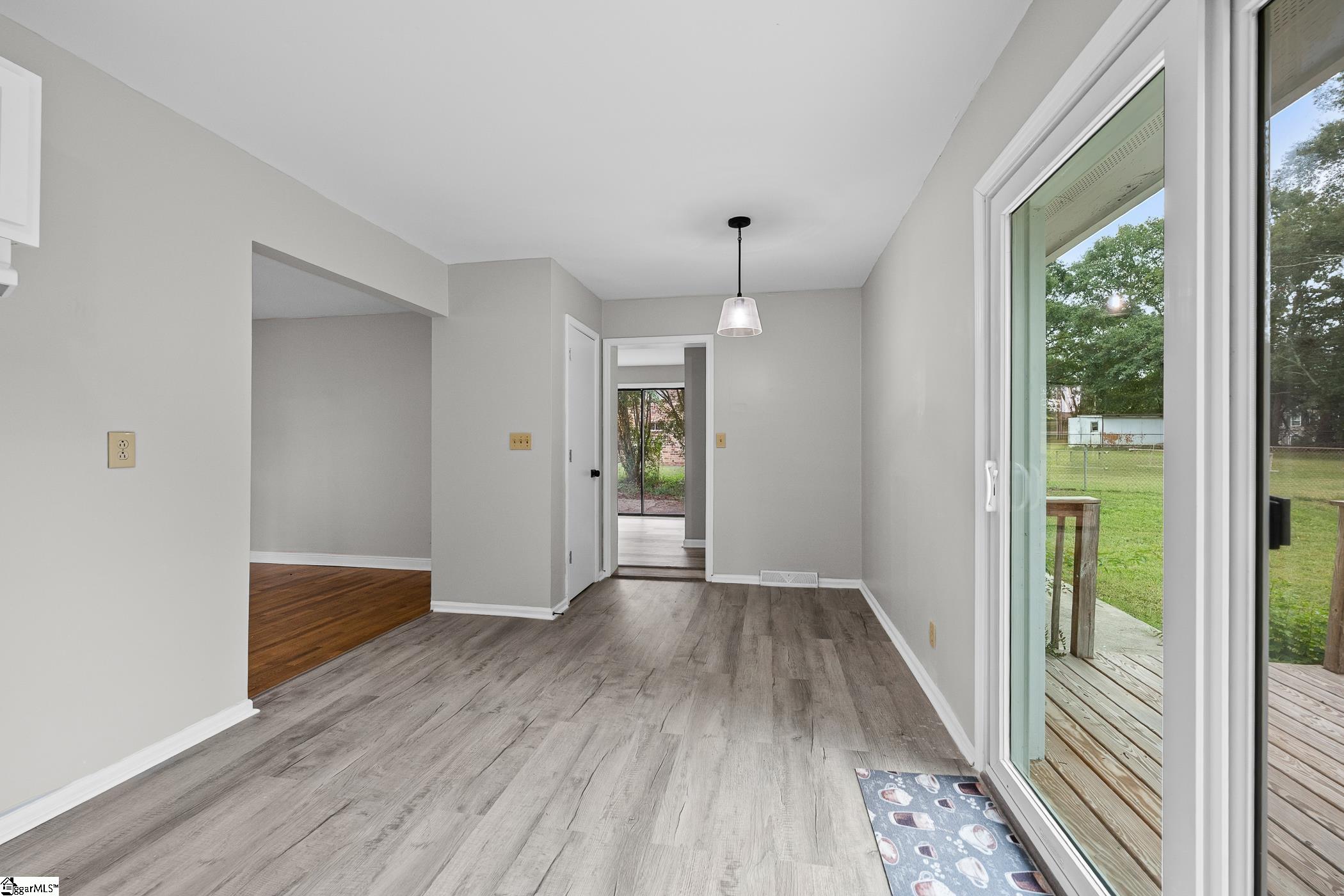 Empty dining area with gray plank flooring and a sliding glass door to the deck.