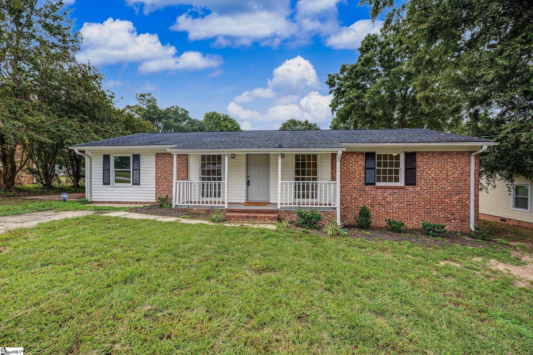 Single-story brick and white-sided house with a covered porch and broad front lawn.