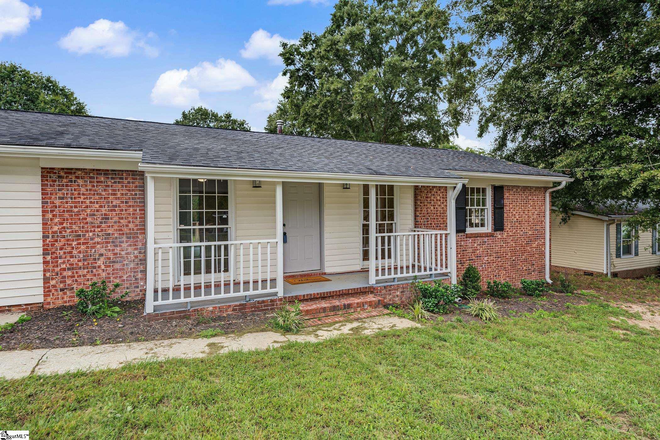 Single-story brick-and-siding home with a white-railed covered porch and grassy front lawn.