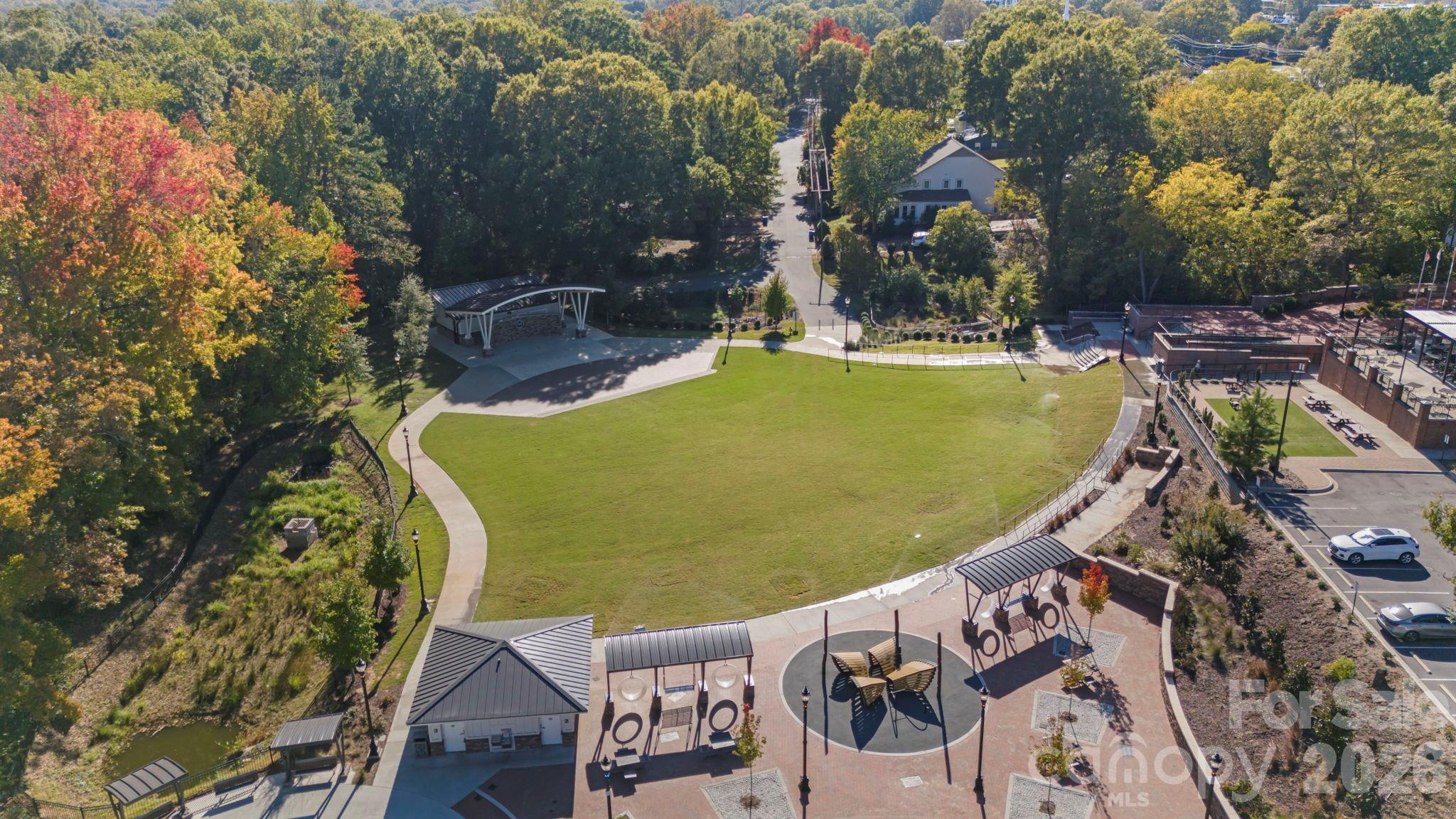 Aerial view of a park with a large lawn, curving paths, and a playground.