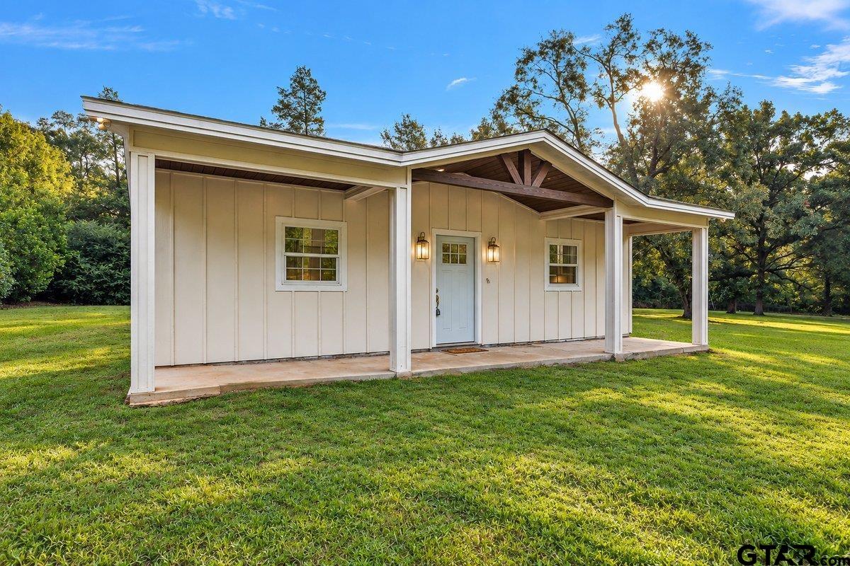 Single-story home with a covered porch and distinctive gabled roof on a tree-lined lawn.
