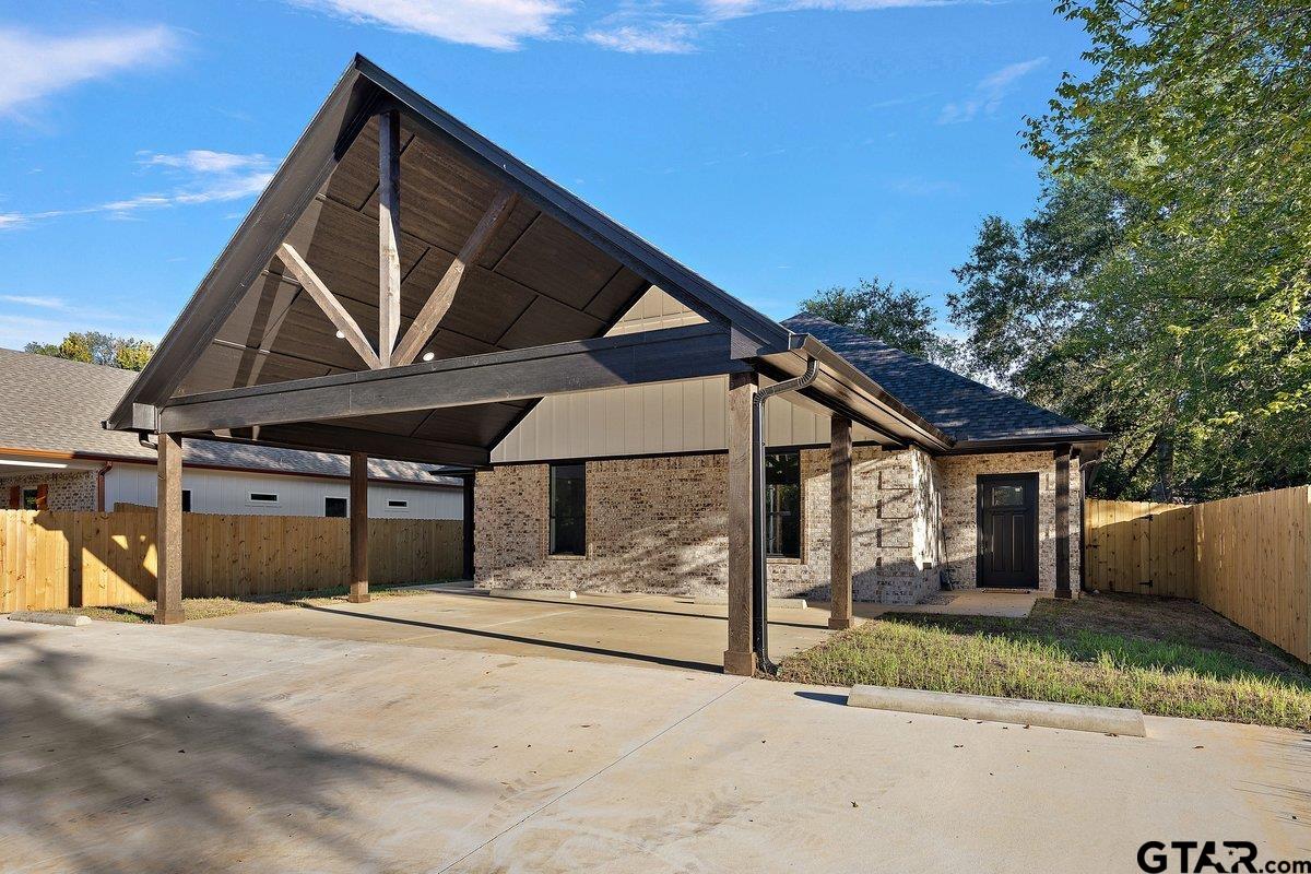 Brick house with a large timber-framed carport and fenced yard.