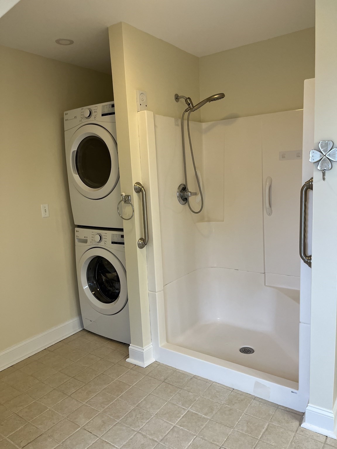 Bathroom with a walk-in shower and stacked front-load washer and dryer.