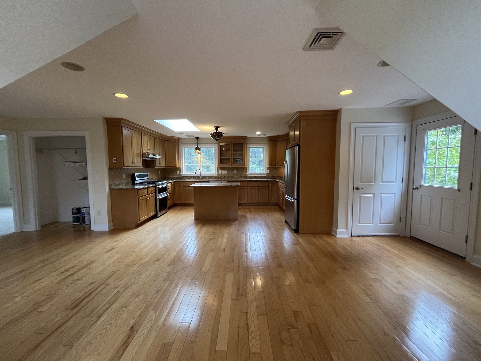 Kitchen with warm wood cabinets, hardwood floors, central island, and skylight.