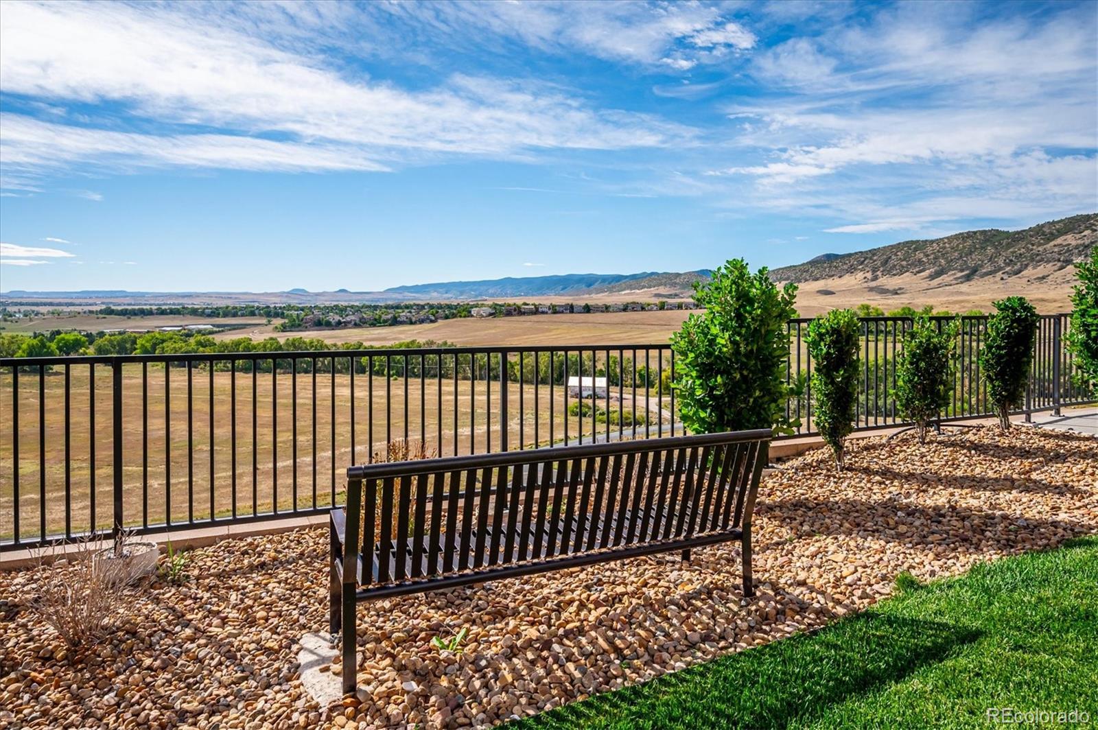 Patio bench and railing overlooking a wide valley and distant hills.