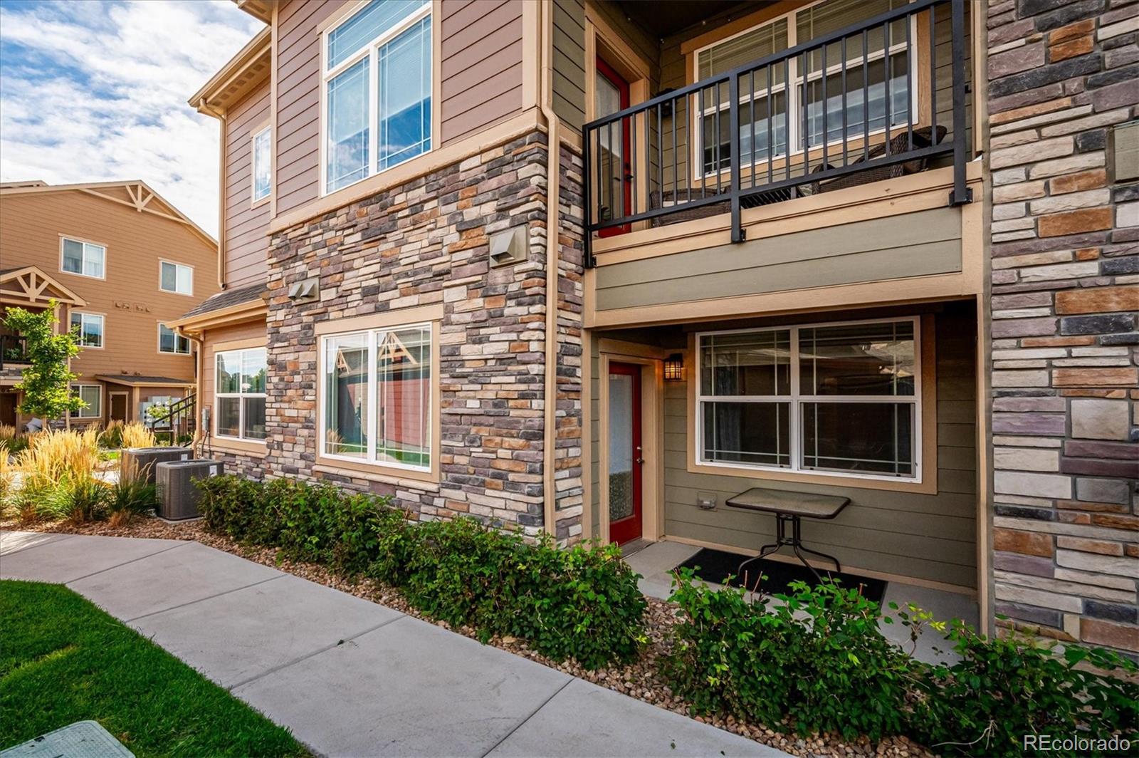 Residence exterior with stone veneer, a covered patio, and an upper balcony.